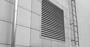 Close-up of a modern building exterior showing a ventilation system and metal ladder.